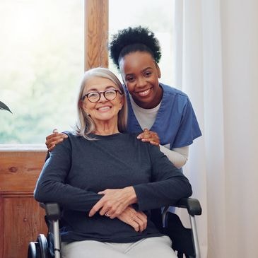 Smiling elderly woman in wheelchair with caring nurse